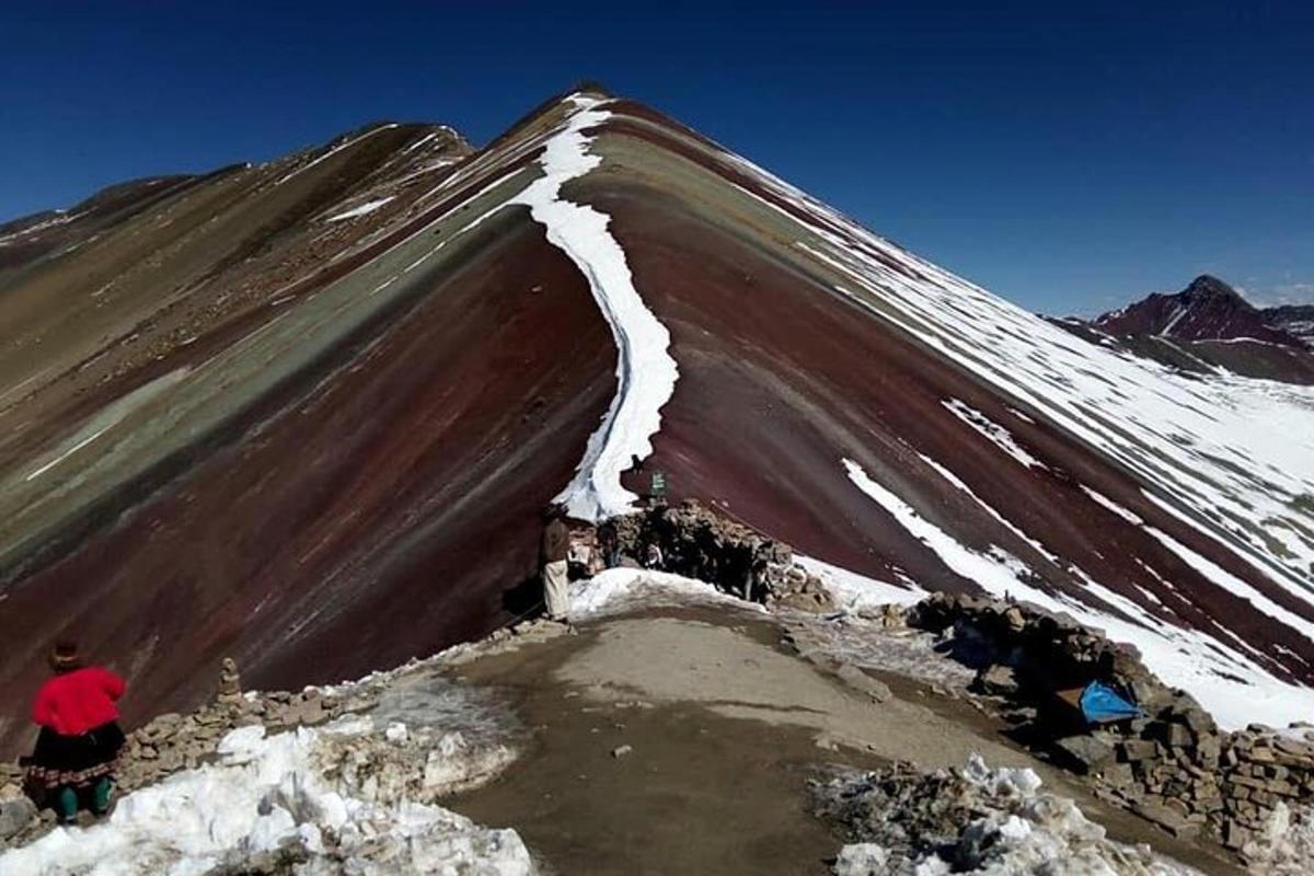 una persona parada en la cima de una montaña cubierta de nieve