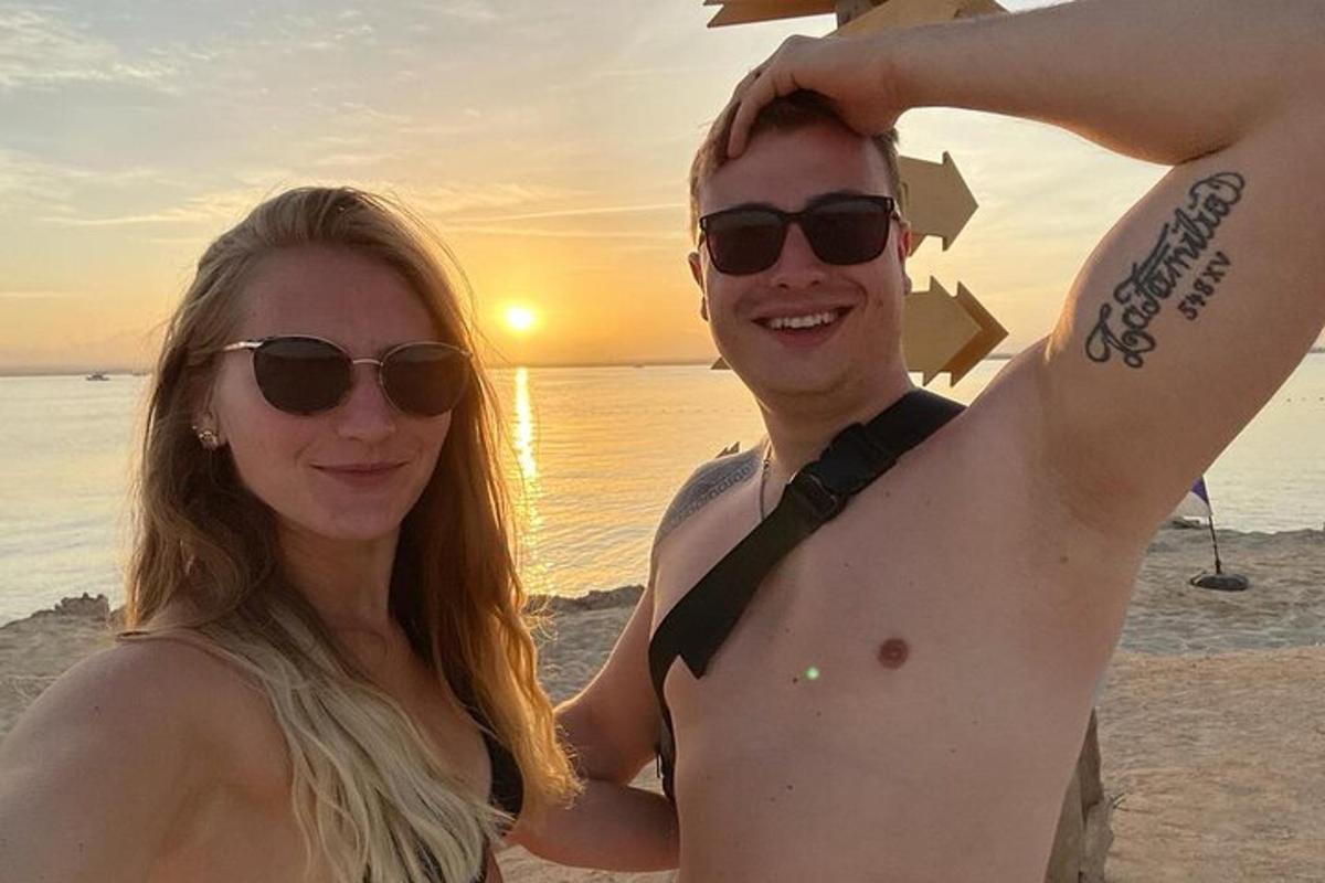 um homem e uma mulher na praia com o pôr do sol