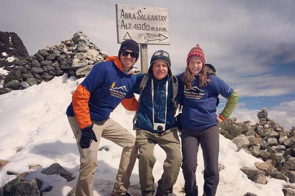 three people standing on top of a snow covered mountain