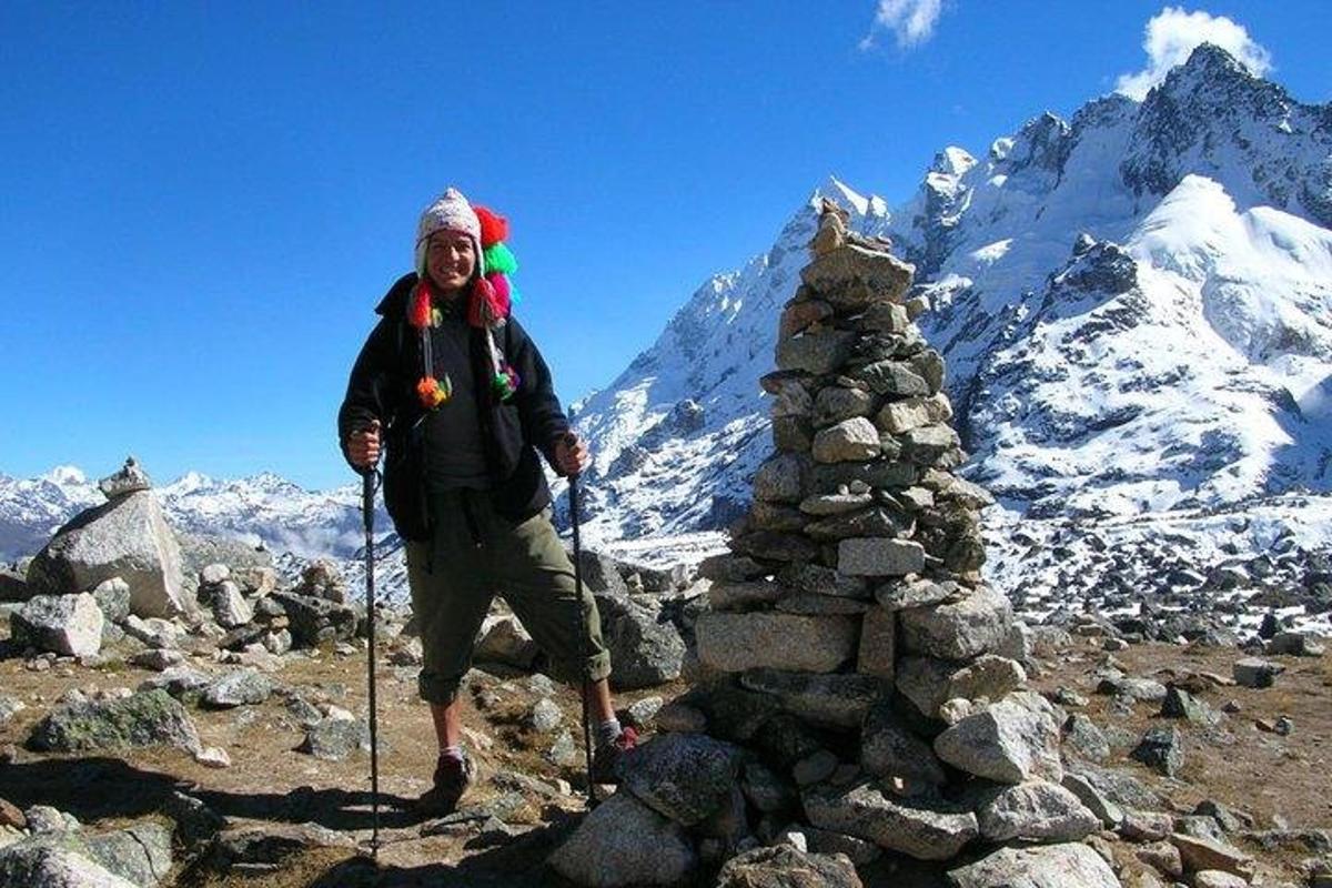 a man standing next to a rock tower on a mountain
