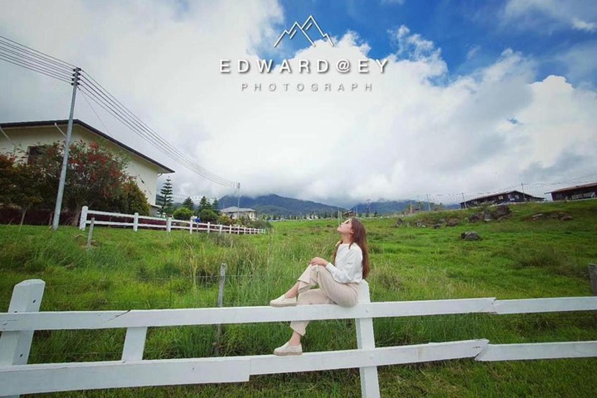 a woman sitting on a white fence in a field