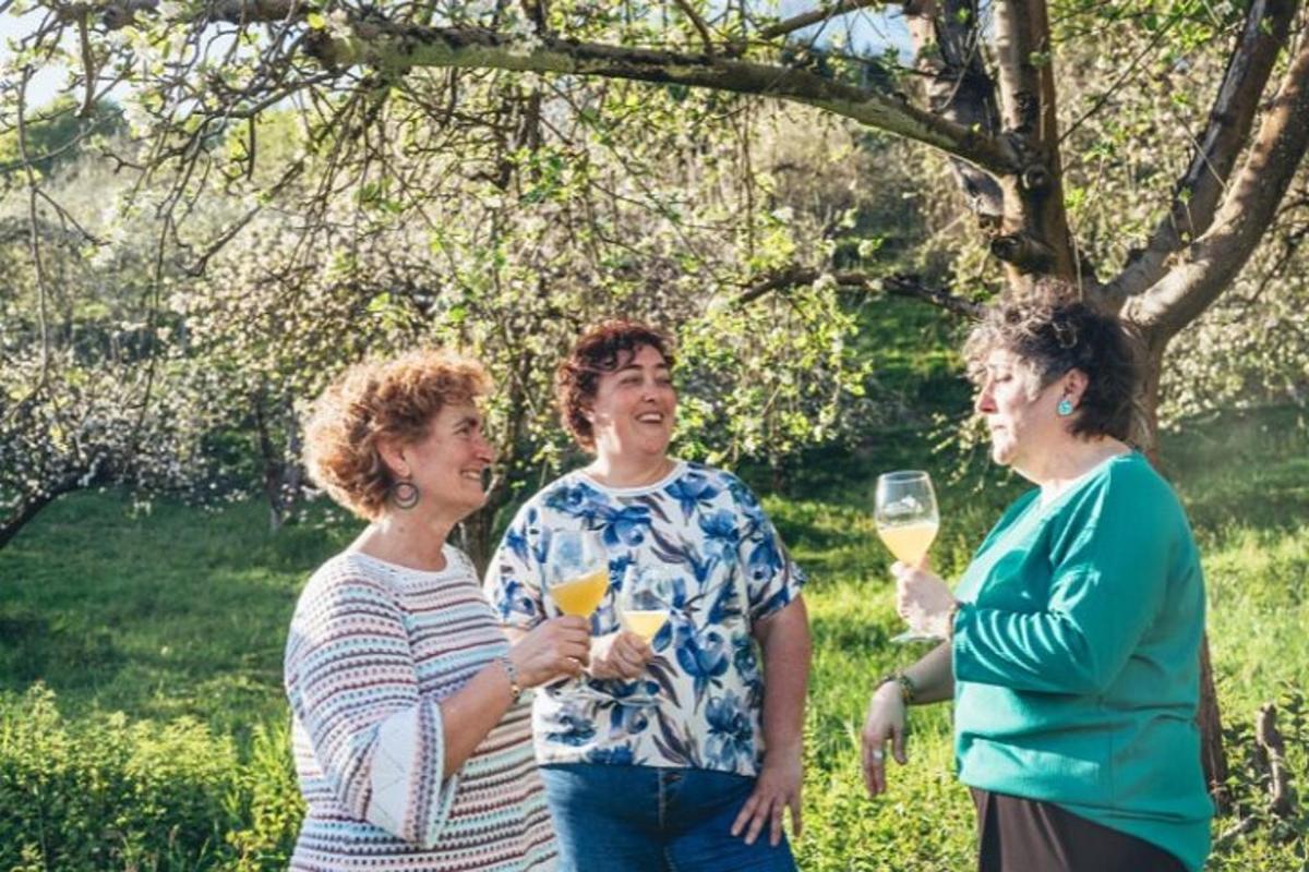 tři ženy stojící vedle sebe a držící sklenice na víno