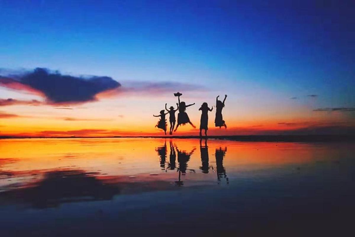 isang grupo ng mga tao na tumatalon sa dalampasigan sa paglubog ng araw