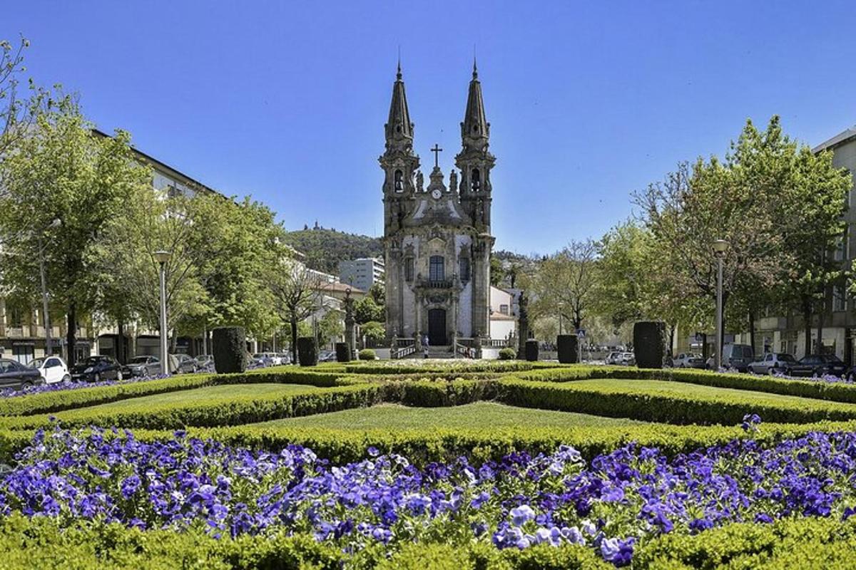 a garden with flowers in front of a building with a tower
