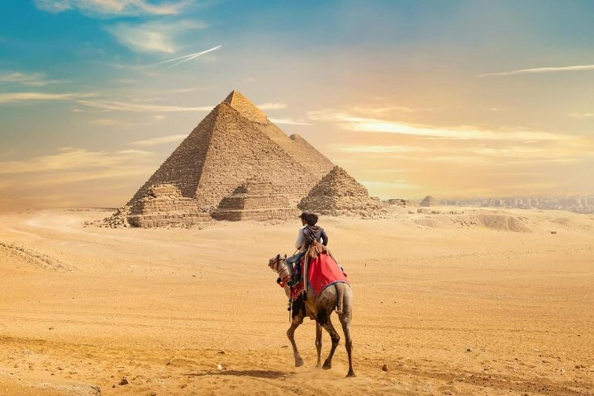 muž jedoucí na koni před pyramidami