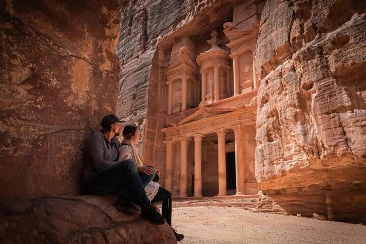 شخصان يجلسان على صخرة أمام مبنى