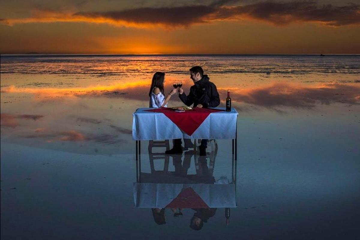 a man and woman sitting at a table on the beach