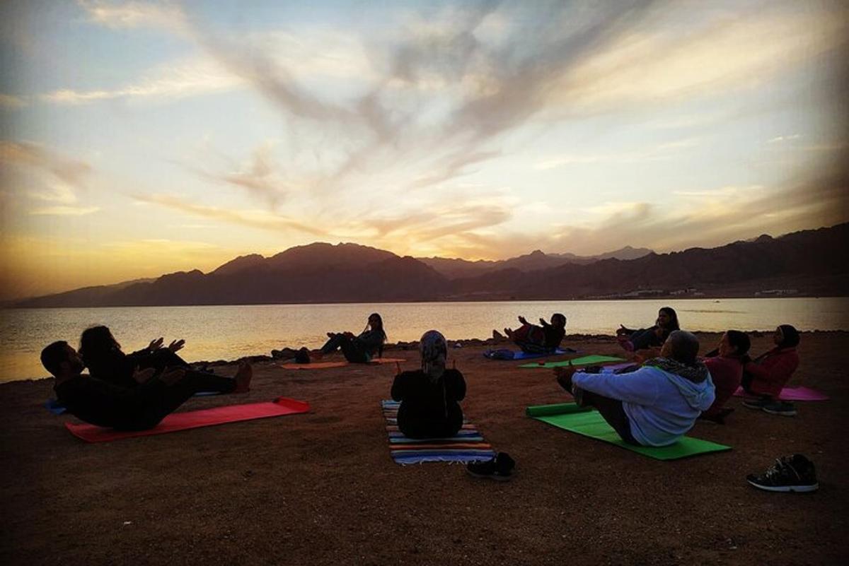 un gruppo di persone sedute sulla spiaggia a guardare il tramonto