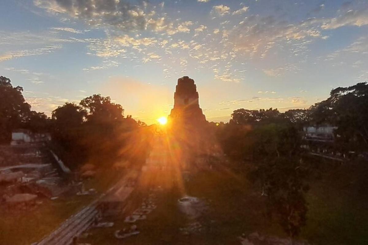 a view of the sun setting behind a rock
