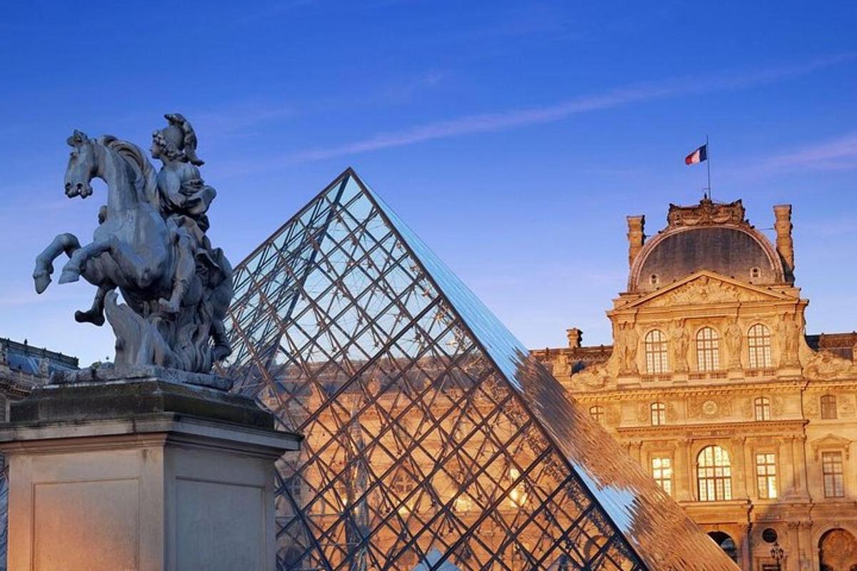 una piràmide de vidre amb una estàtua davant d'un edifici