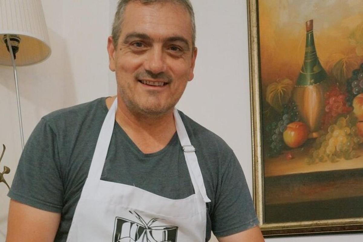 un uomo che indossa un grembiule bianco davanti a un dipinto