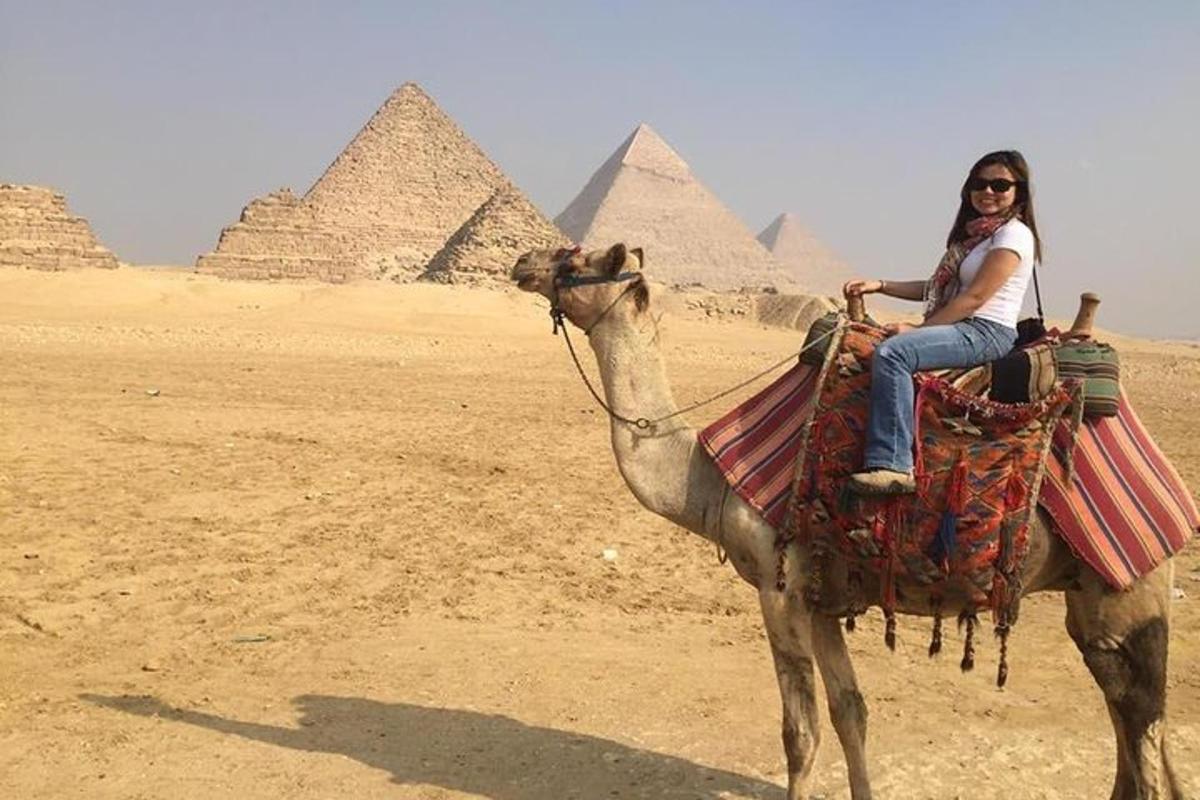 žena jedoucí na velbloudovi před pyramidami