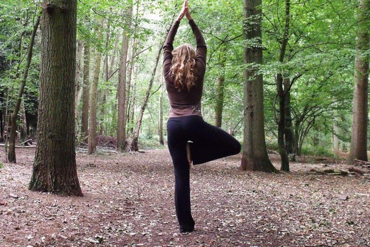 a woman doing a yoga pose in the woods