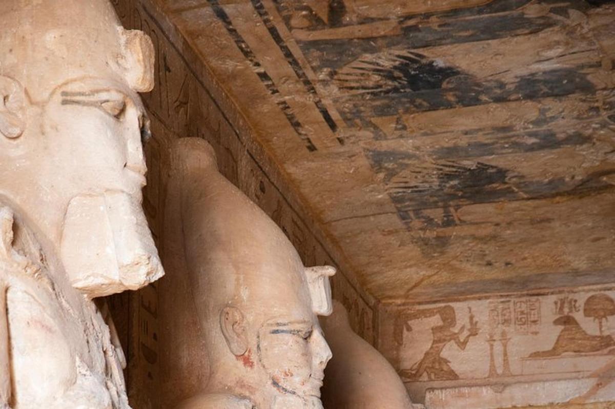 una statua seduta accanto a un soffitto decorato con dipinti