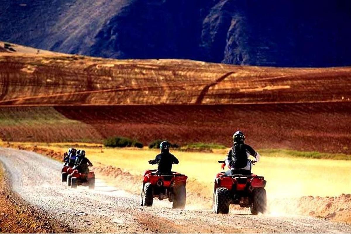 three people riding motorcycles on a dirt road