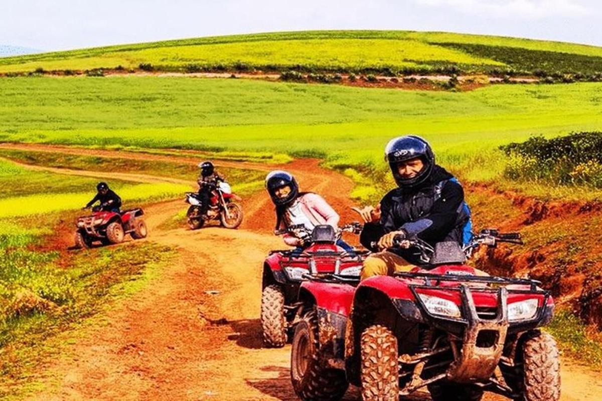 three people riding on atvs on a dirt road