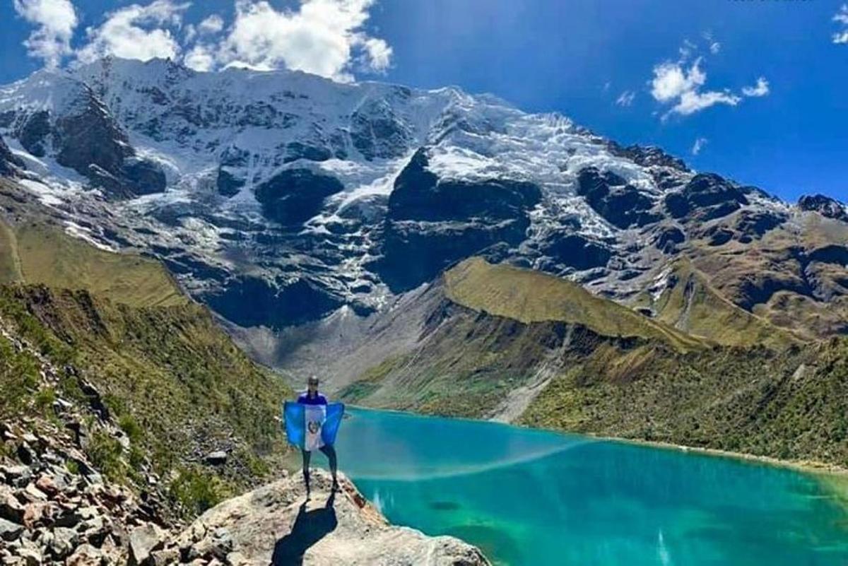 osoba stojící na vrcholu hory s výhledem na jezero