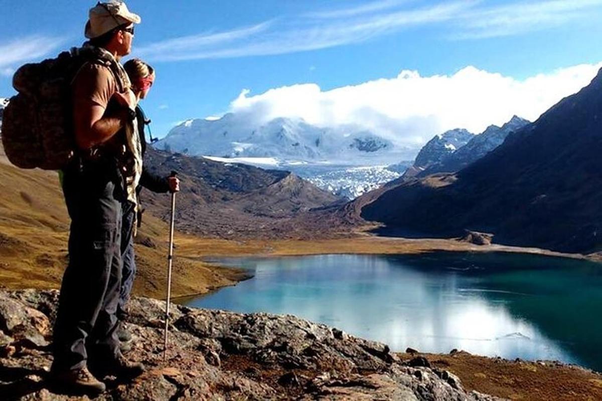 duas pessoas em pé no topo de uma montanha com vista para um lago