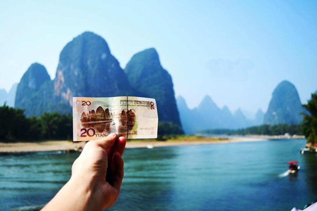 a person holding a dollar bill in front of a river