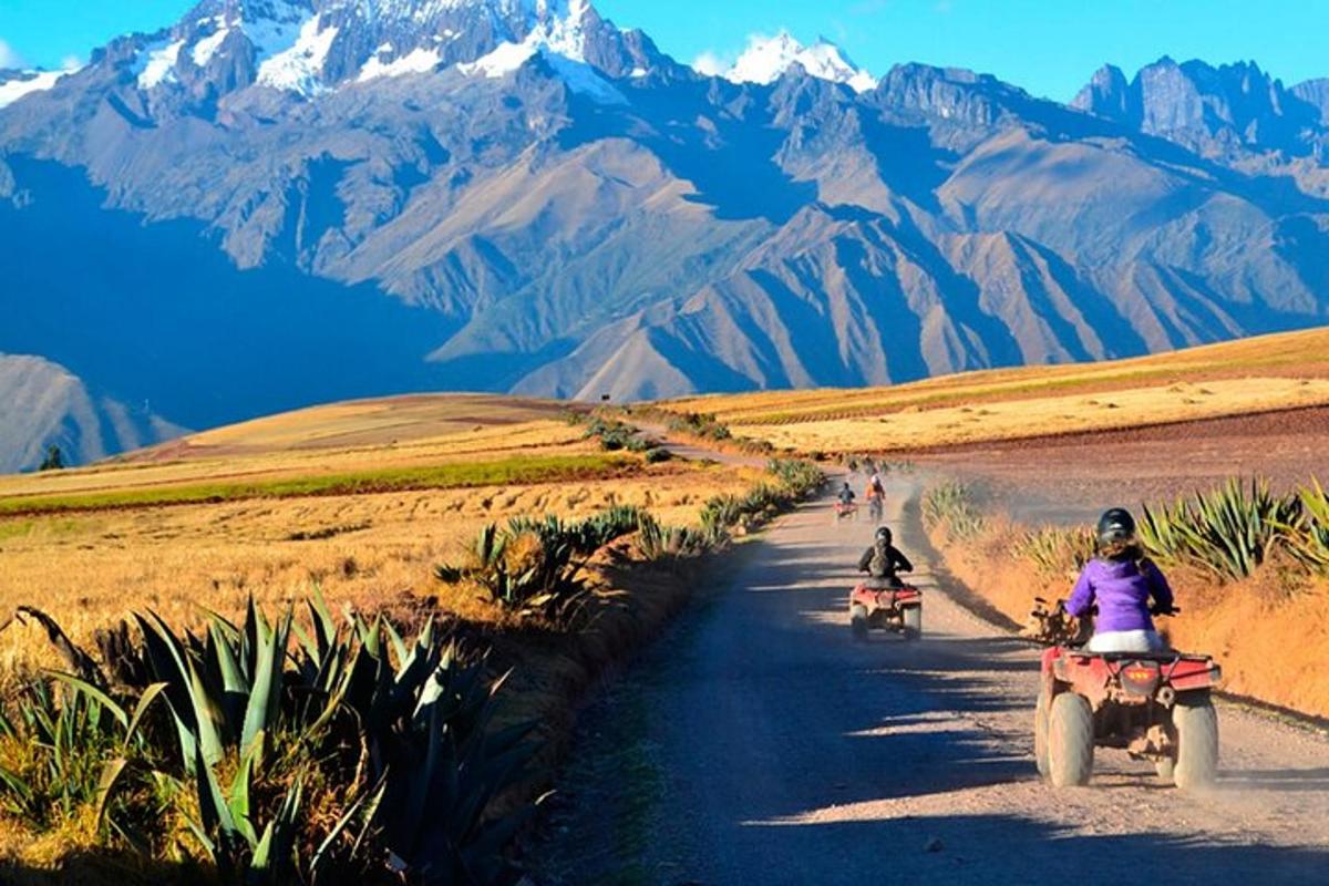 duas pessoas andando de motocicleta em uma estrada de terra com montanhas ao fundo