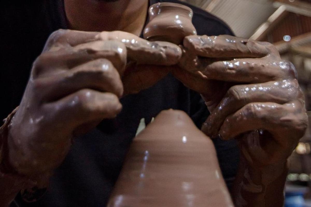 a man with muddy hands holding a vase