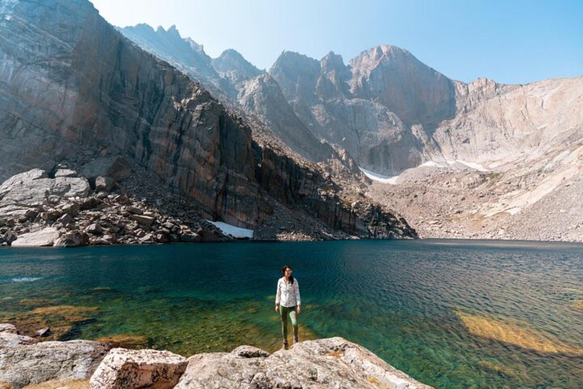 a person standing on a rock near a mountain lake