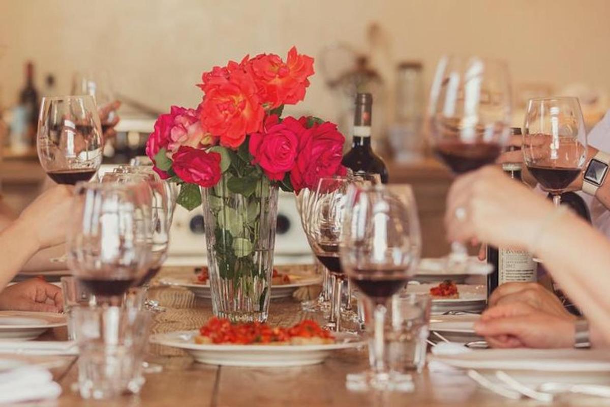 un tavolo con un vaso di fiori rossi e bicchieri da vino