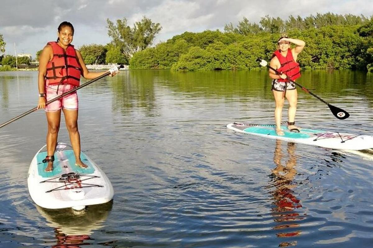 dues persones estan dretes sobre taules de paddle surf a l'aigua