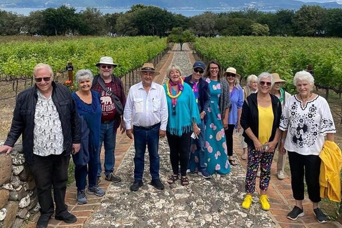 Un grupo de personas de pie frente a un viñedo.