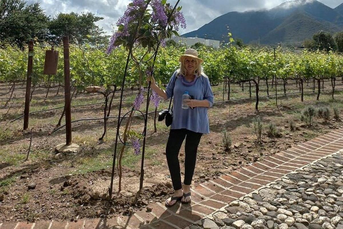 Una mujer está de pie junto a un árbol con flores moradas.