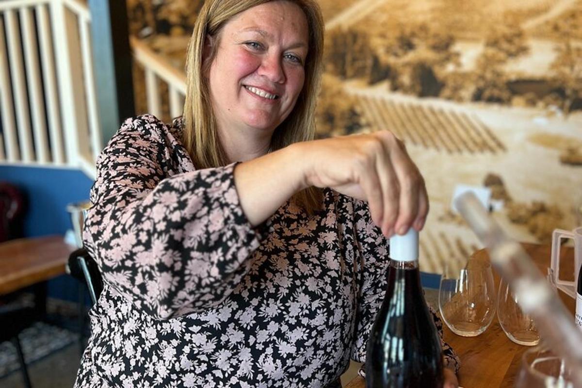 a woman sitting at a table opening a bottle of wine