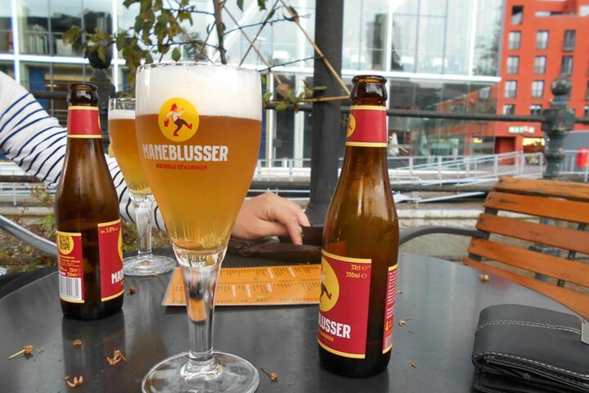 Dos botellas de cerveza sobre una mesa con un vaso.