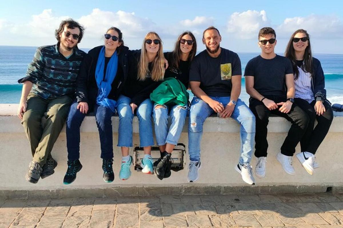 un grup de persones assegudes en un mur a la platja