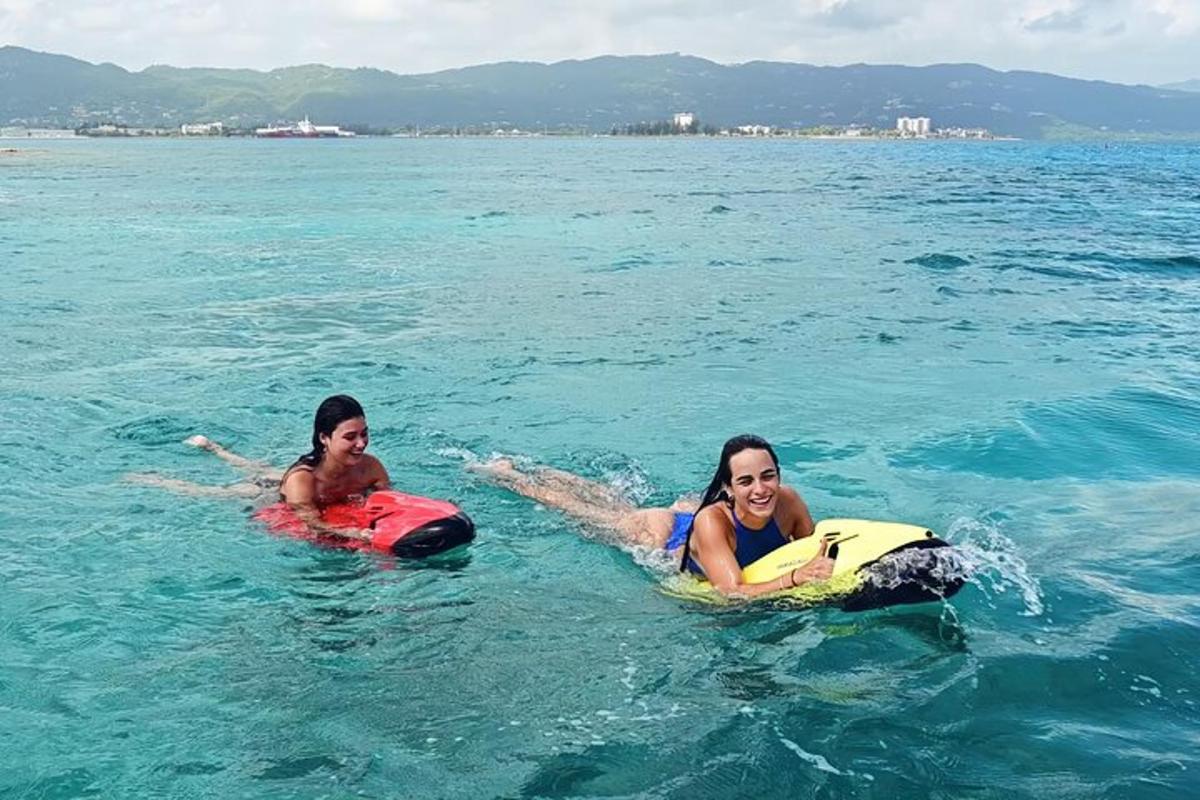 zwei Mädchen liegen auf Boogie-Boards im Wasser