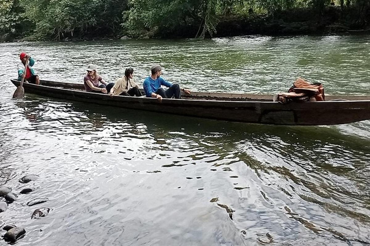 un grup de oameni stând într-o barcă pe un râu