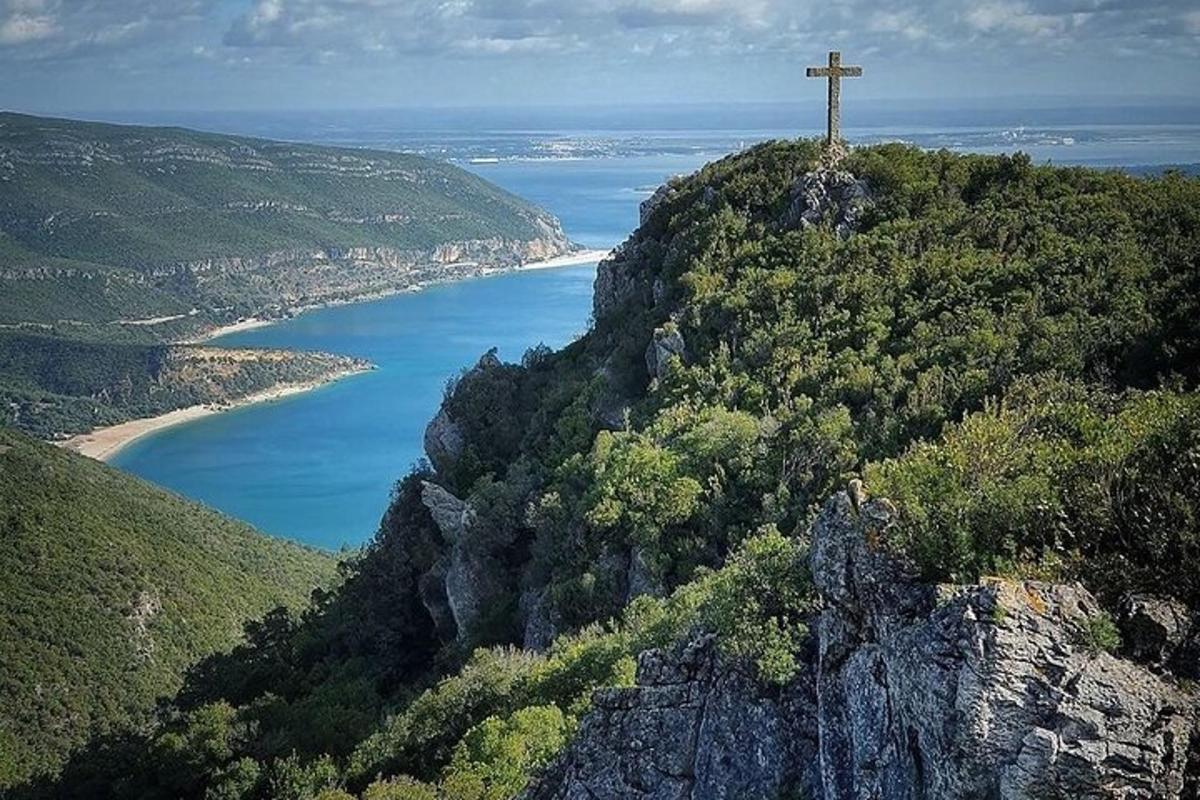 una creu al cim d'una muntanya a prop d'una massa d'aigua