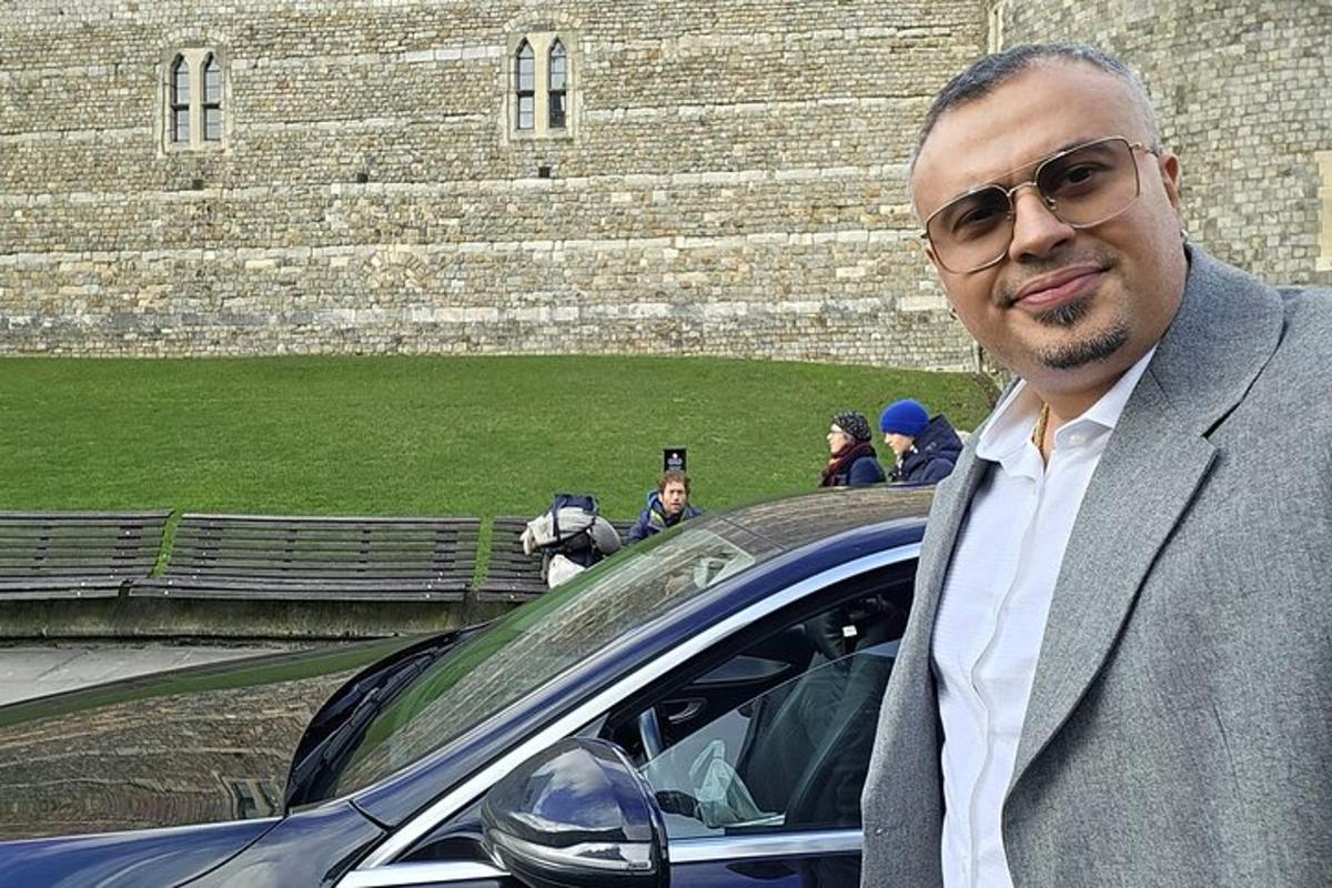 ένας άντρας με κοστούμι που στέκεται δίπλα σε ένα αυτοκίνητο