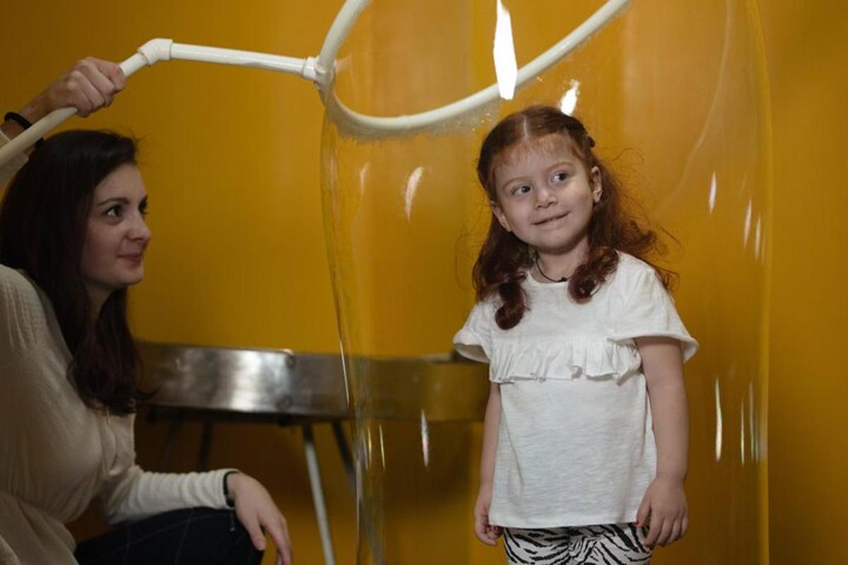 uma menina parada em frente ao espelho com um secador de cabelo