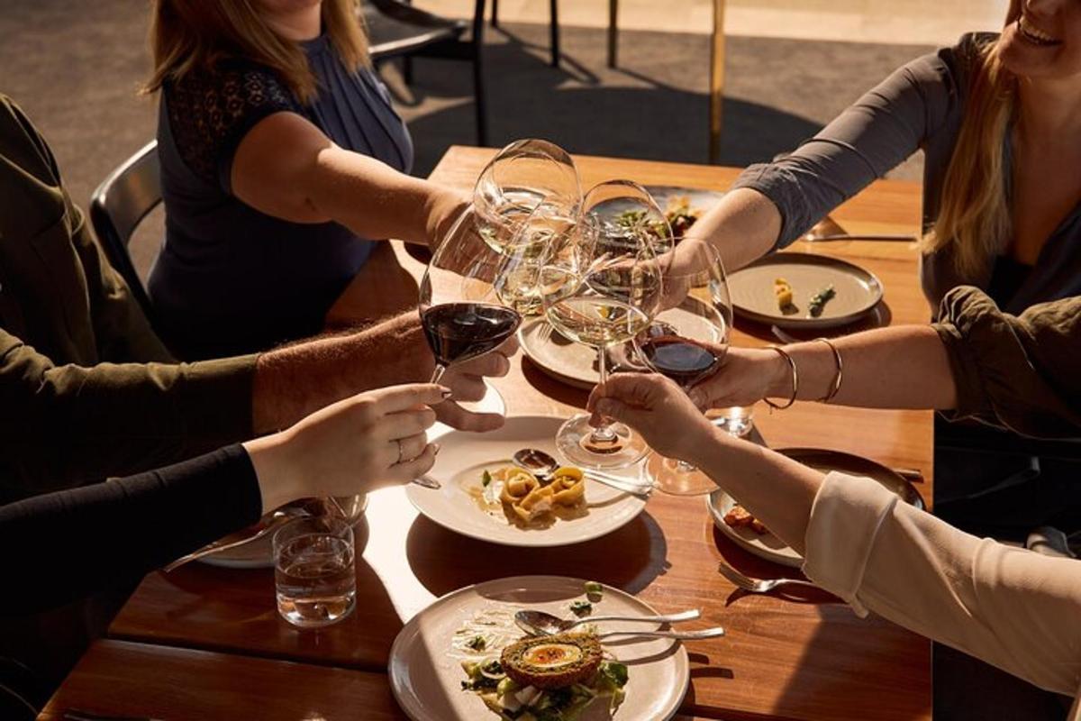 um grupo de pessoas sentadas ao redor de uma mesa com taças de vinho