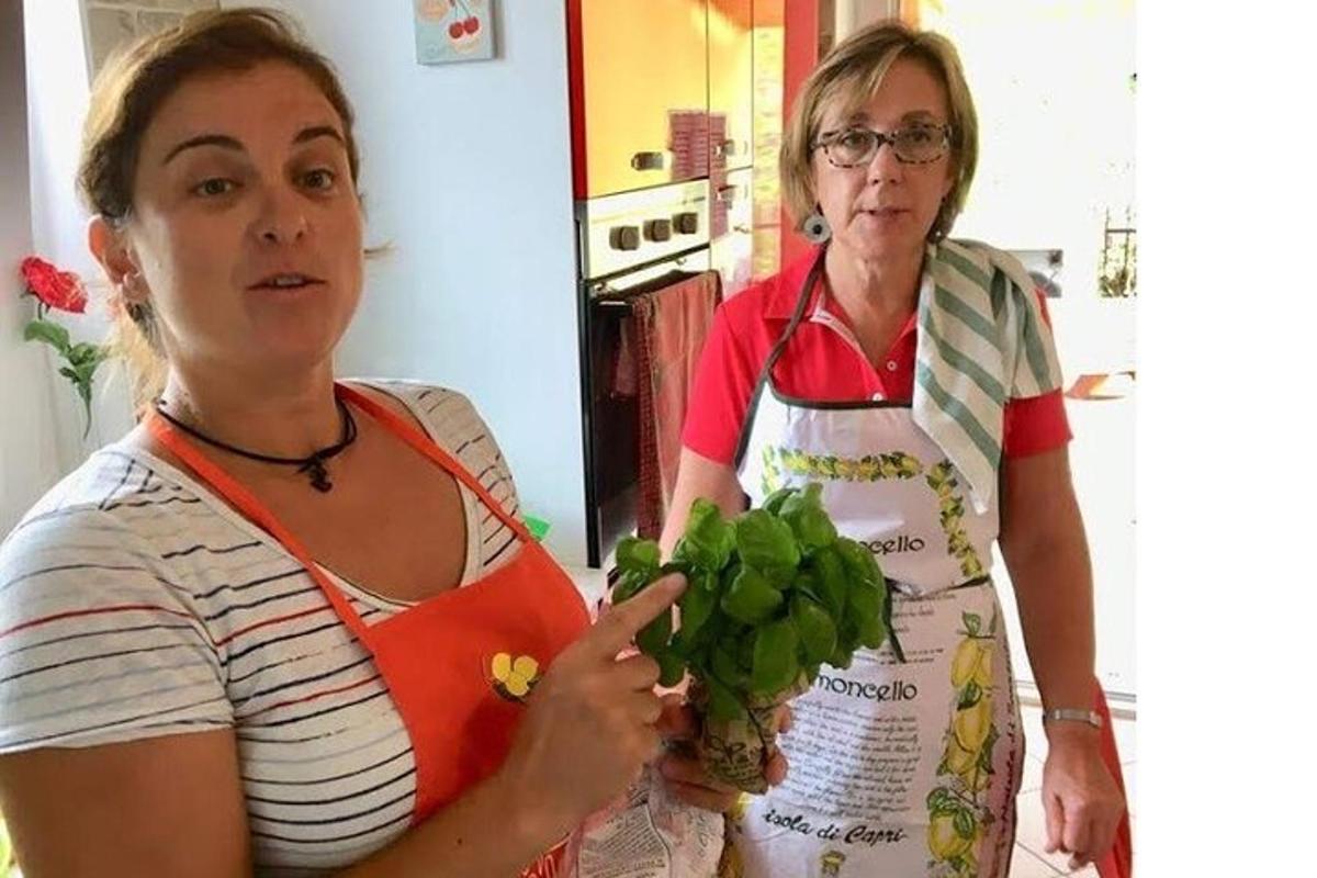 dvě ženy stojící v kuchyni a držící svazek zeleniny