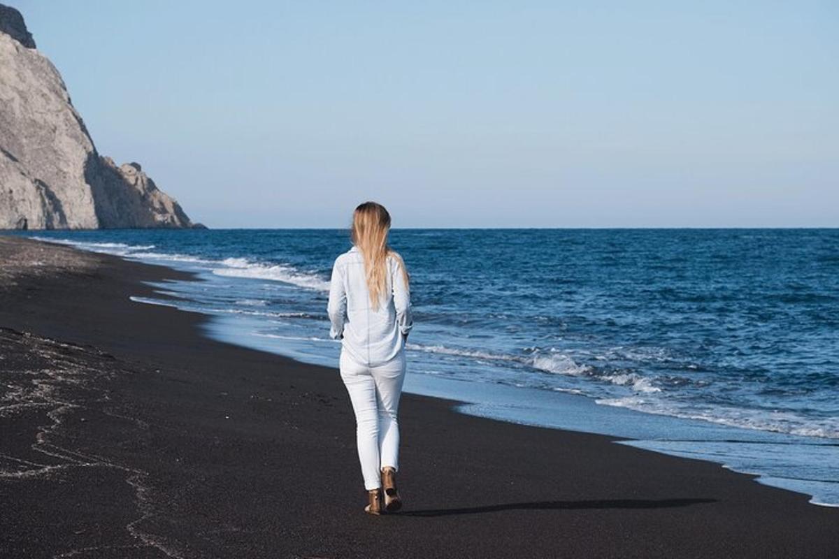 kobieta spacerująca po plaży w pobliżu oceanu