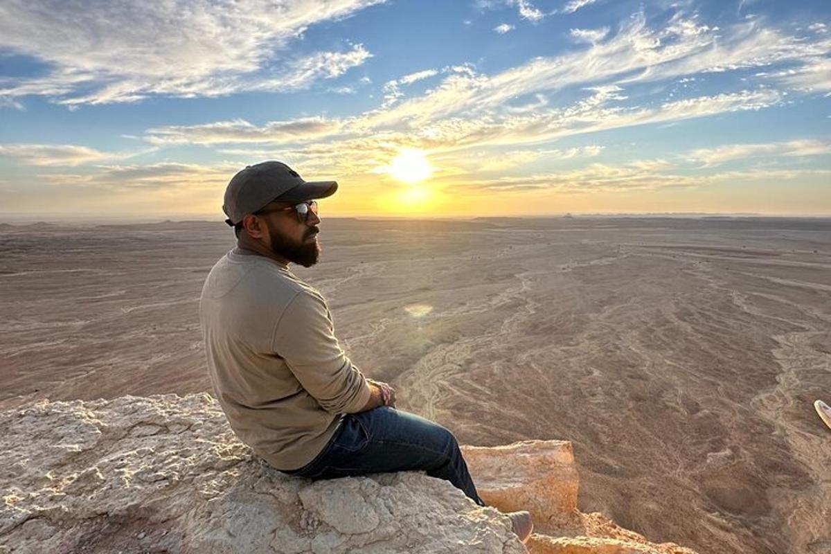 a man sitting on a rock watching the sunset