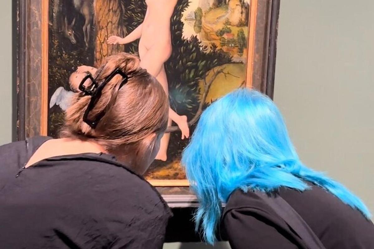 a woman with blue hair looking at a painting