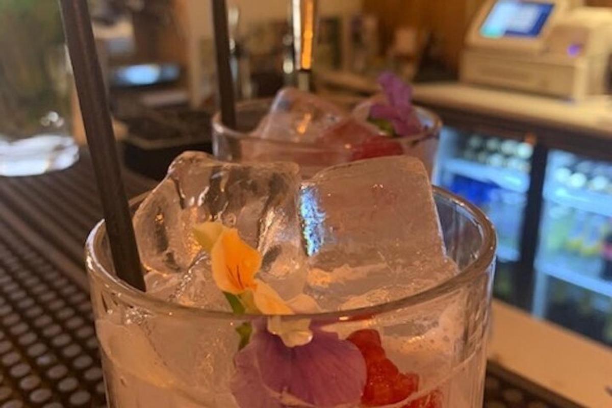 Una bebida con hielo y una flor sobre una mesa.