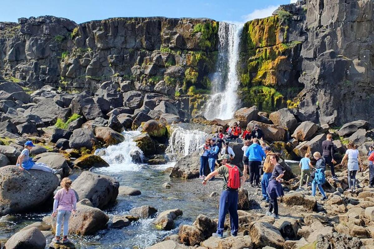 um grupo de pessoas em pé sobre rochas perto de uma cachoeira
