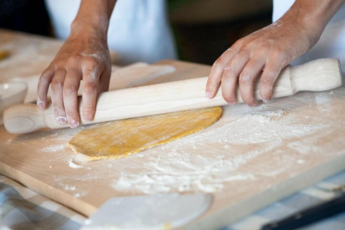 una persona che stende un impasto su un tagliere di legno