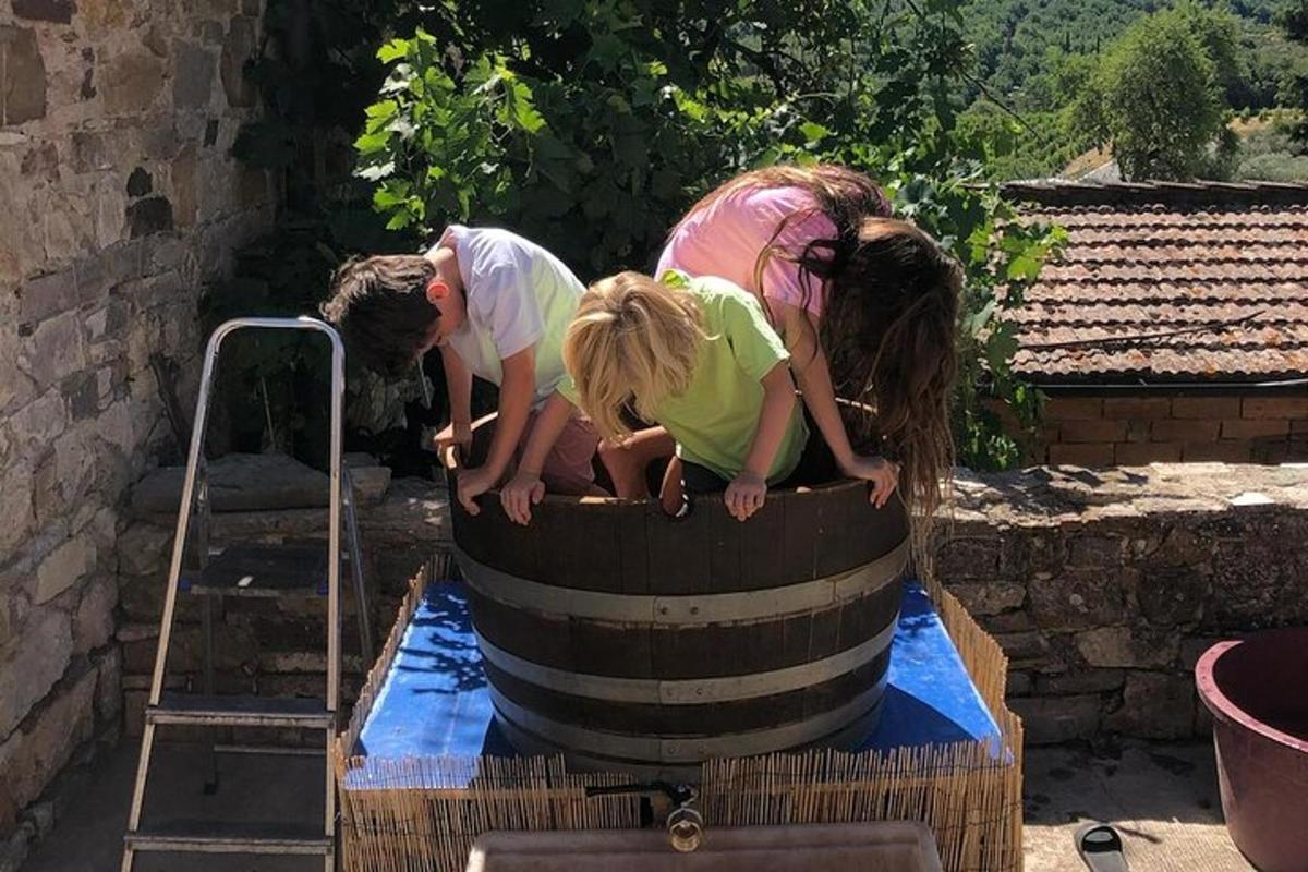 três crianças brincando em um barril de água