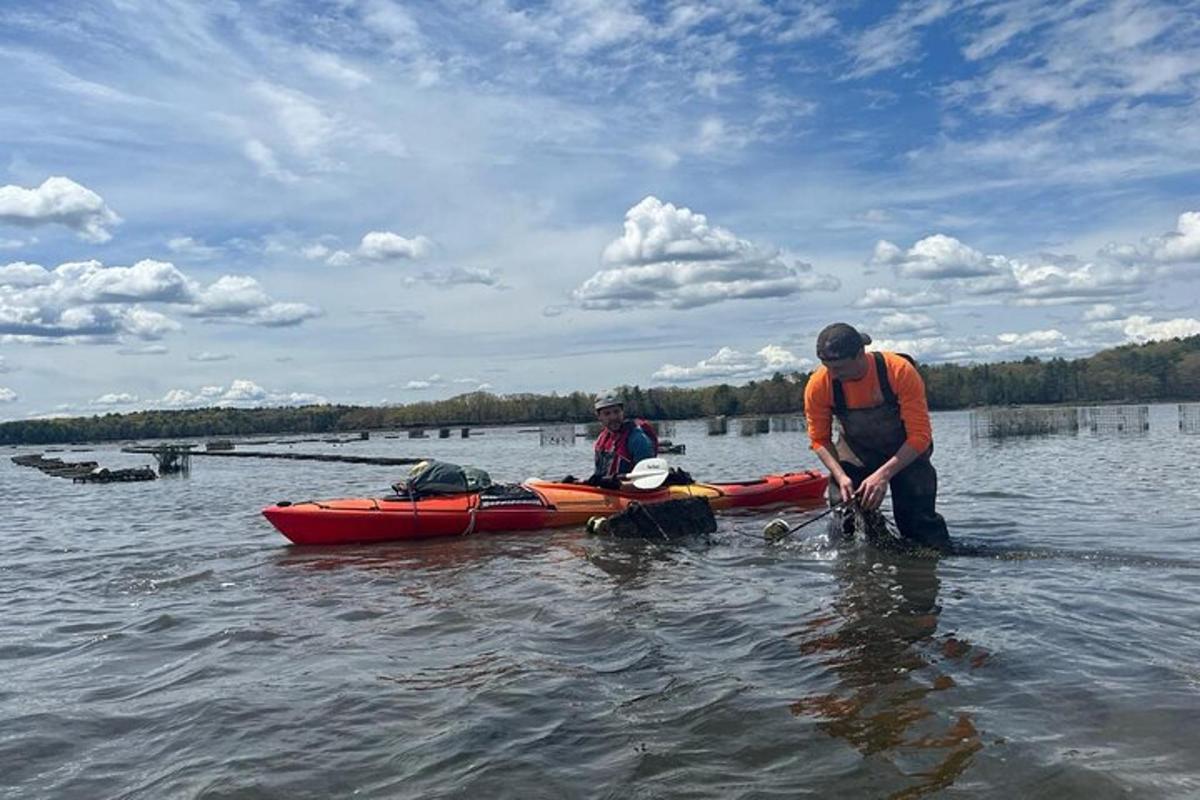 two men standing in the water next to a kayak