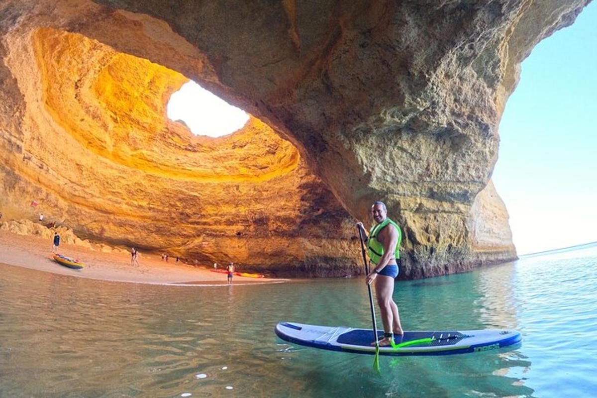 una persona su una tavola da paddle in acqua di fronte a una grotta