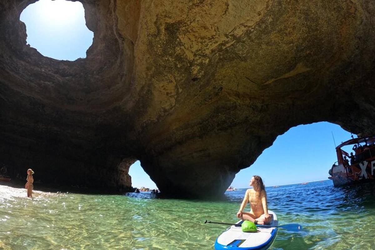 una donna seduta su un kayak di fronte a una grotta